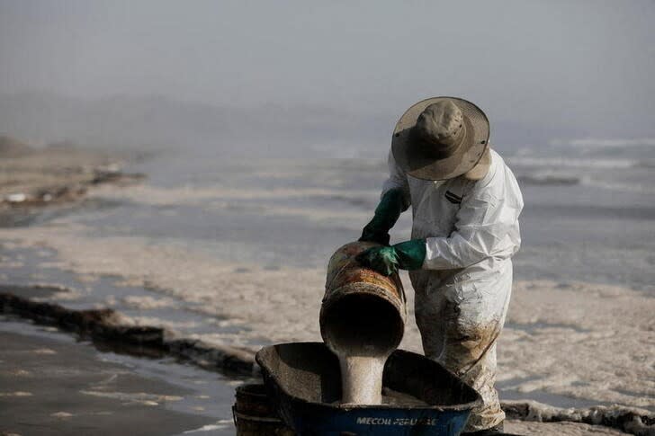 IMAGEN DE ARCHIVO. Un trabajador limpia un derrame de petróleo, en medio del descarge de un tanquero, causado por olas anormales provocadas por una erupción volcánica submarina en Tonga, frente a la costa de Lima, en Ventanilla, Perú