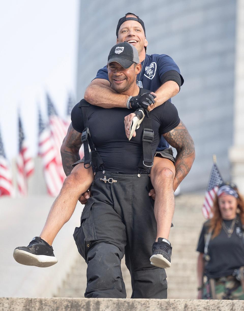 Christopher Hartzler, of the Wooster fire and police departments, carries Plain Township resident Adam Davis down the McKinley National Memorial stairs on Monday during an event commemorating those lost in the Sept. 11, 2001, attacks.