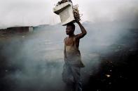 'E-Waste in Ghana' by Kai Löeffelbein. This striking image shows a man with an old computer on his head in the middle of a waste dump. Up to 50m tonnes of toxic electronic waste accumulate annually in the world and many are exported from developed countries to developing nations (Kai Löeffelbein)