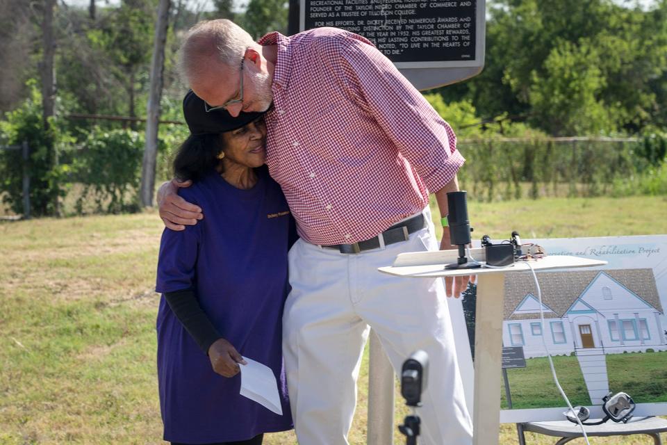 Taylor Mayor Brandt Rydel hugs Jennifer Harris, president of the Dickey Museum & Multipurpose Center, during a news conference at the site of the former James L. Dickey House in Taylor on Monday. Last year the center burned down. The St. David's Foundation donated $500,000 to help rebuild the facility, which will house a wellness center for low-income people.