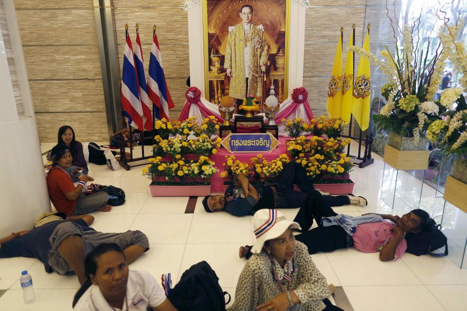 Anti-government protesters rest under the picture of Thailand's King Bhumibol Adulyadej at the entrance of a building of the Finance Ministry after occupying it in Bangkok