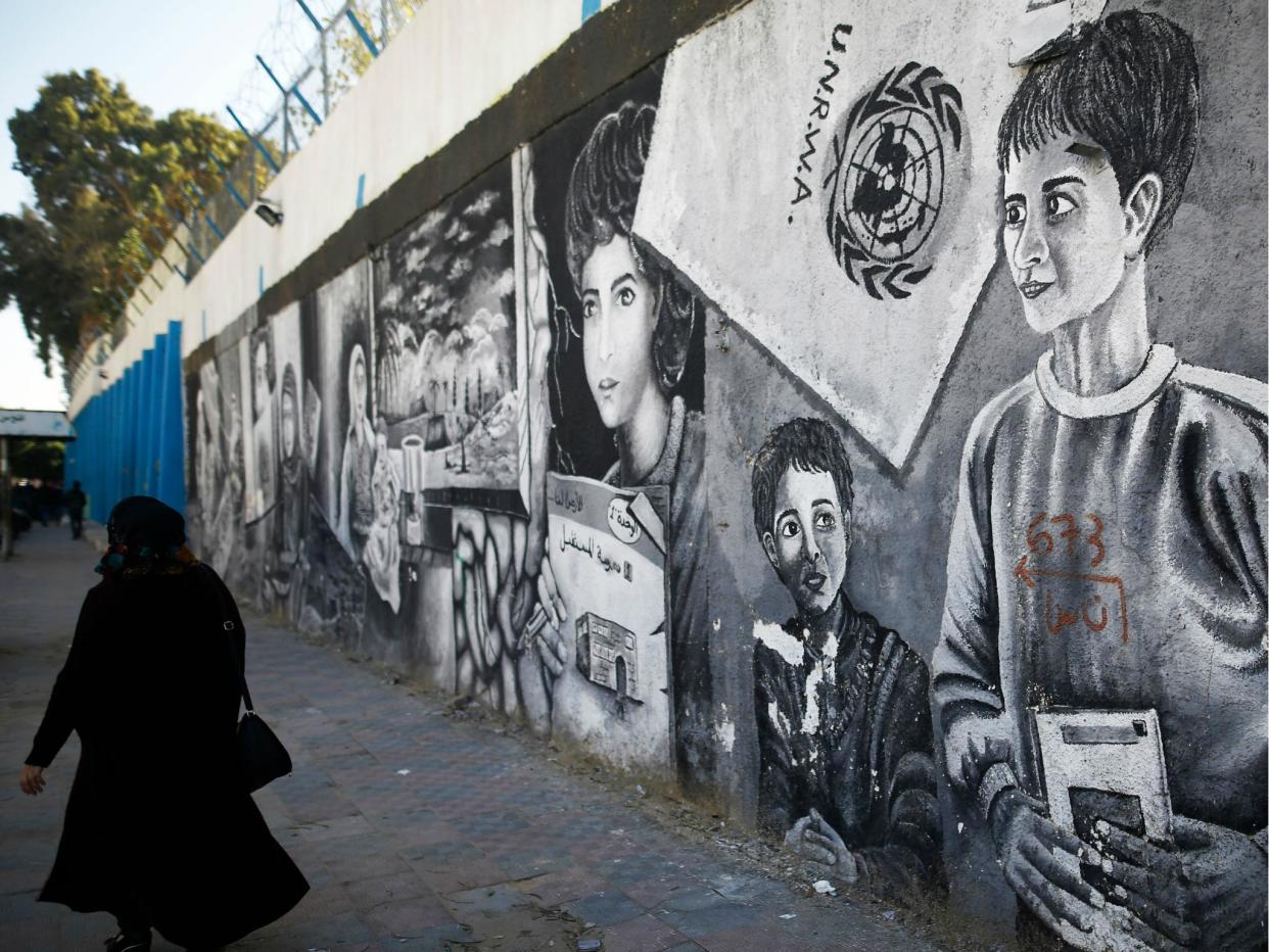 A Palestinian woman walks past graffiti painted on the wall of the building of the UNRWA headquarters in Gaza City on 8 January 2018: MOHAMMED ABED/AFP/Getty Images