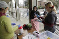 In this March 27, 2020 photo, Laura Spracklin, center, picks up medication for opioid addiction at a clinic in Olympia, Wash., that is currently meeting patients outdoors and offering longer prescriptions in hopes of reducing the number of visits and the risk of infection due to the outbreak of the new coronavirus. The coronavirus pandemic is challenging the millions who struggle with drug and alcohol addiction and threatening America's progress against the opioid crisis, said Dr. Caleb Alexander of Johns Hopkins' school of public health. (AP Photo/Ted S. Warren)