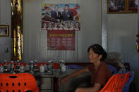 A woman rests near a poster showing Chinese leaders including Chinese President Xi Jinping and Chinese Premier Li Keqiang in Pingtan in eastern China's Fujian province, Saturday, Aug. 6, 2022. Taiwan said Saturday that China's military drills appear to simulate an attack on the self-ruled island, after multiple Chinese warships and aircraft crossed the median line of the Taiwan Strait following U.S. House Speaker Nancy Pelosi's visit to Taipei that infuriated Beijing. (AP Photo/Ng Han Guan)