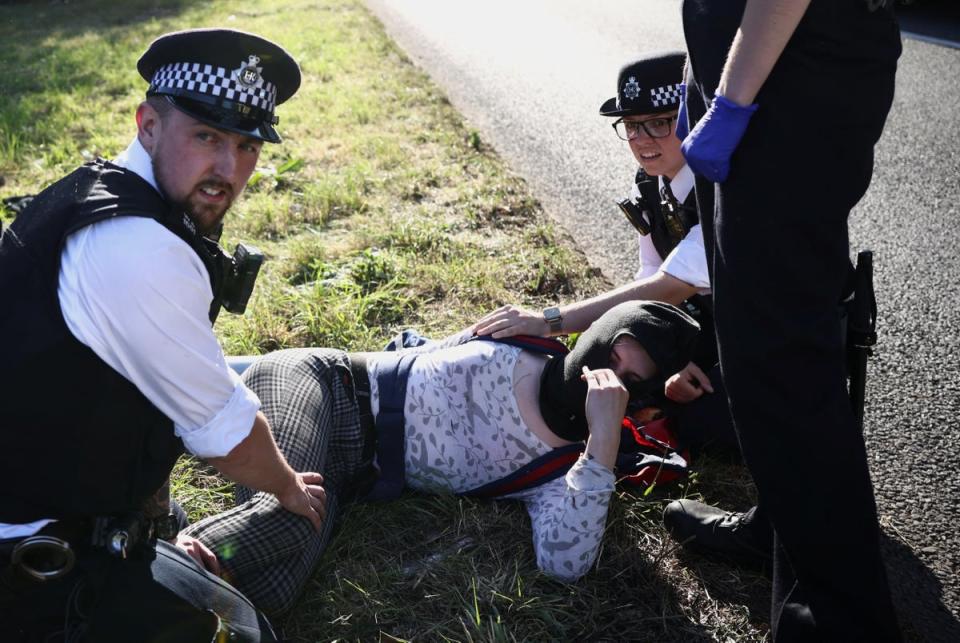 Police officers try to remove an activist blocking the road (REUTERS)