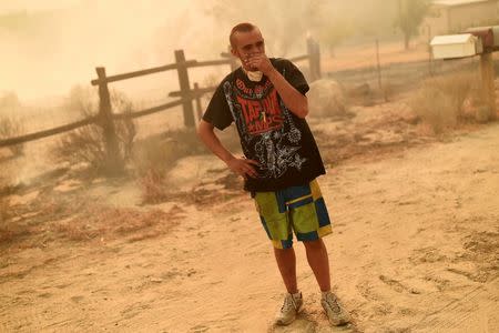 Alex Thurman, 20, stands in front of a smoldering field as the Erskine Fire burns near Weldon, California, U.S. June 24, 2016. Thurman said he thinks the fire destroyed his neighboring home. REUTERS/Noah Berger