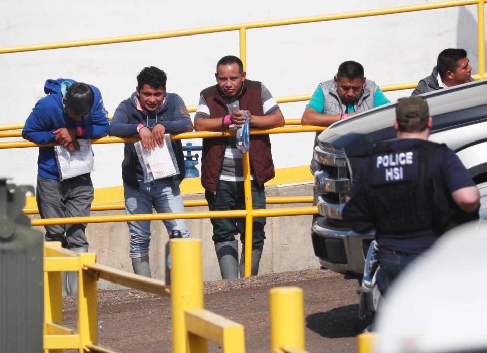 Handcuffed workers await transportation to a processing center following a raid by U.S. immigration officials at Koch Foods Inc., plant in Morton, Miss. U.S. immigration officials raided several Mississippi food processing plants on Wednesday and signaled that the early-morning strikes were part of a large-scale operation targeting owners as well as employees.