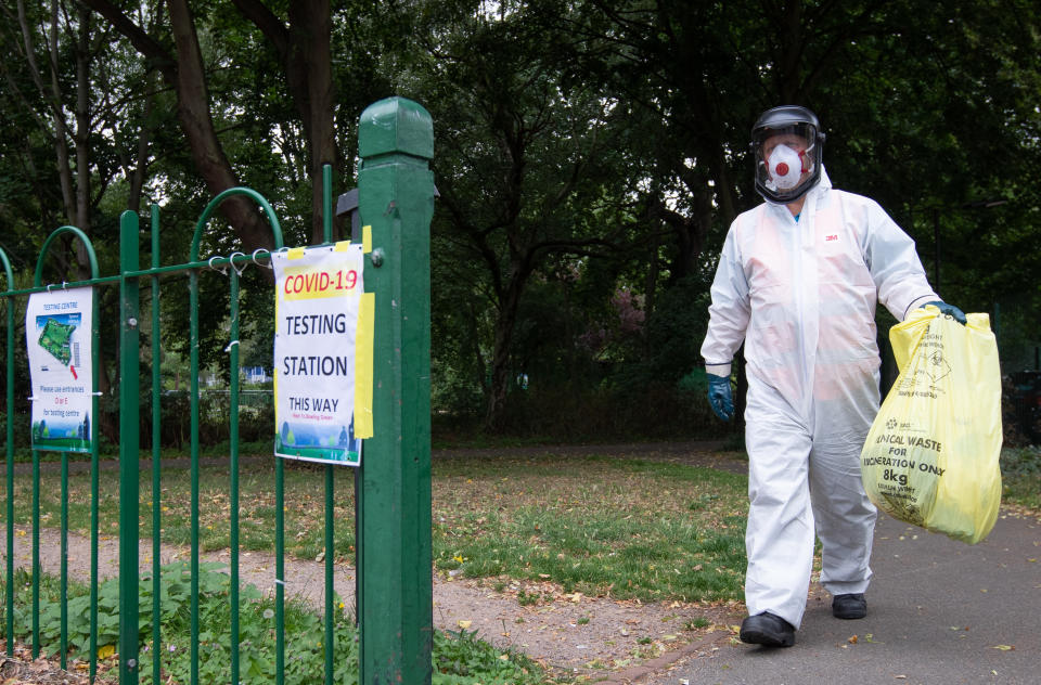 A worker for Leicester City Council carries a bag of clinical waste away from a Covid-19 testing station at Spinney Hill Park in Leicester where localised coronavirus lockdown restrictions have been in place since June 29, with non-essential shops ordered to close and people urged not to travel in or out of the area. (Photo by Joe Giddens/PA Images via Getty Images)