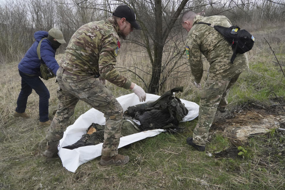 Ukrainian servicemen pack the dead body of a Russian soldier, killed in a recent battle in the Kharkiv region, Ukraine, Saturday, April 8, 2023. (AP Photo/Andrii Marienko)