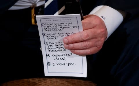 President Donald Trump holds notes during a listening session with high school students and teachers in the State Dining Room of the White House in Washington, - Credit: AP