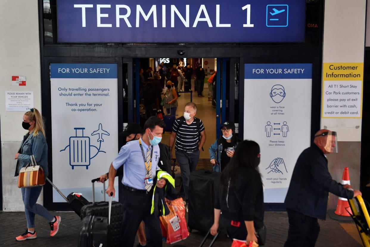 Passengers wearing a face mask or covering due to the COVID-19 pandemic, react as they exit Terminal 1 after landing at Manchester Airport in Manchester, north west England on July 27, 2020. - Tour operator TUI has cancelled all British holidays to mainland Spain from Monday until August 9, after the UK government's decision to require travellers returning from the country to quarantine. The newly-imposed rule to self-isolate, abruptly introduced at midnight Saturday hours after being announced, follows a surge in coronavirus cases in parts of Spain in recent weeks. (Photo by Anthony Devlin / AFP) (Photo by ANTHONY DEVLIN/AFP via Getty Images)