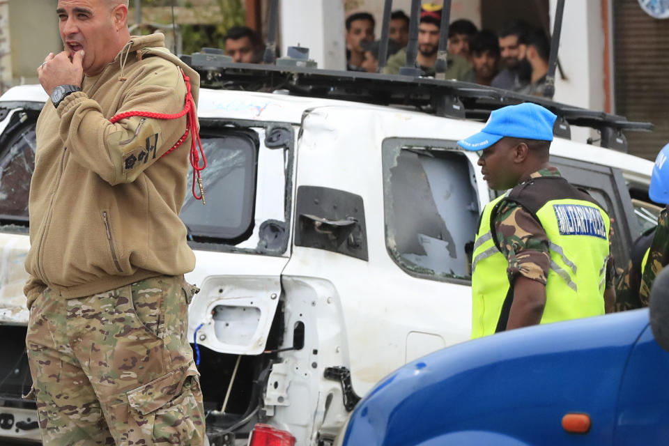 Officials stand next to a damaged UN peacekeeper vehicle at the scene where a UN convoy came under gunfire in the Al-Aqbiya village, south Lebanon, Thursday, Dec. 15, 2022. (AP Photo/Mohammed Zaatari)