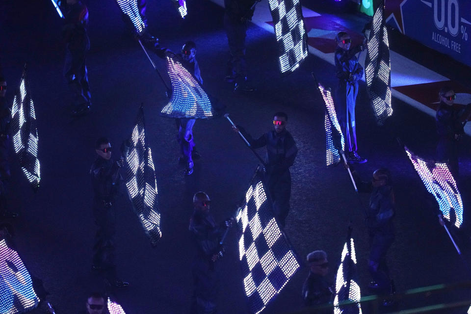 Performers wave flags during an opening ceremony for the Formula One Las Vegas Grand Prix auto race, Wednesday, Nov. 15, 2023, in Las Vegas. (AP Photo/Darron Cummings)