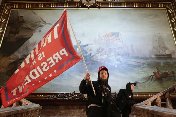 WASHINGTON, DC - JANUARY 06: A protester holds a Trump flag inside the US Capitol Building near the Senate Chamber on January 06, 2021 in Washington, DC. Congress held a joint session today to ratify President-elect Joe Biden's 306-232 Electoral College win over President Donald Trump. A group of Republican senators said they would reject the Electoral College votes of several states unless Congress appointed a commission to audit the election results. (Photo by Win McNamee/Getty Images)