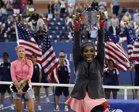 Serena Williams of the U.S. raises her trophy after defeating Victoria Azarenka of Belarus (L, holding runner up trophy) in their women's singles final match at the U.S. Open tennis championships in New York September 8, 2013. REUTERS/Mike Segar