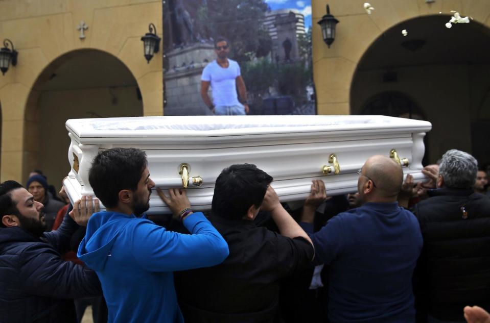 Relatives and friends of Elias Wardini, a Lebanese man who was killed in the New Year's Eve Istanbul nightclub attack, carry his coffin past his portrait on a church wall, in Beirut, Lebanon, Tuesday, Jan. 3, 2017. Three Lebanese citizens were killed in the shooting and four injured. (AP Photo/Hussein Malla)