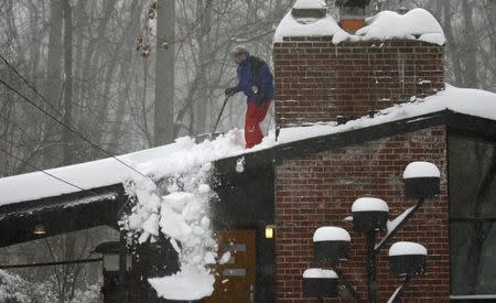 Paul Boos of Falls Church, Virginia, shovels snow from his roof as a blizzard hits the east coast January 23,2016. REUTERS/Kevin Lamarque
