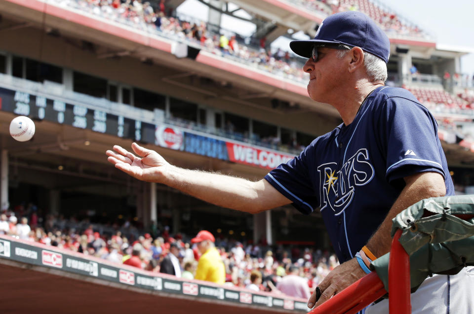 Tampa Bay Rays manager Joe Maddon tosses a ball back to a fan after autographing it prior to the start of a baseball game against the Cincinnati Reds, Saturday, April 12, 2014, in Cincinnati. (AP Photo/Al Behrman)