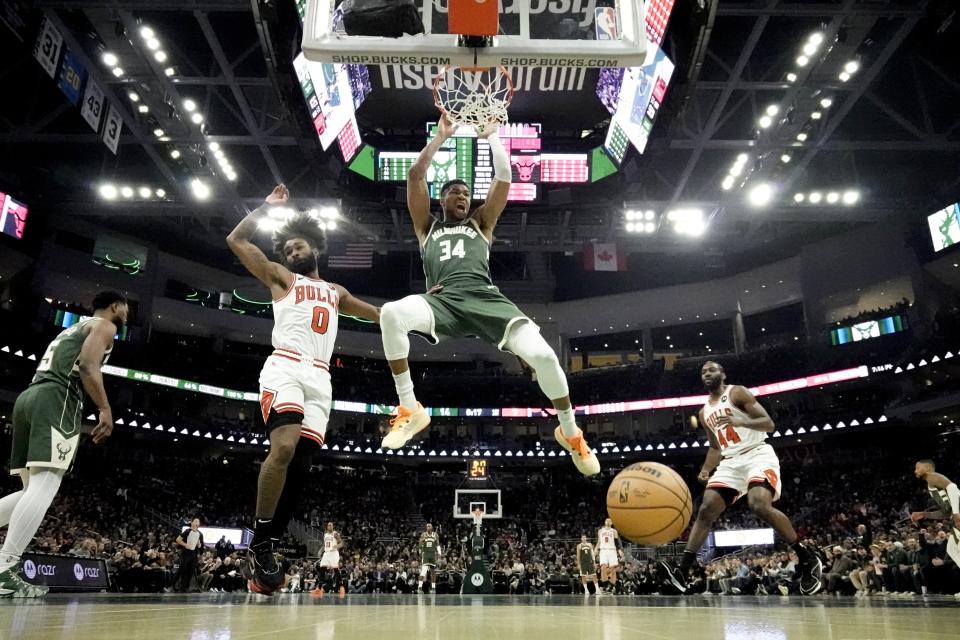 Milwaukee Bucks' Giannis Antetokounmpo dunks over Chicago Bulls' Coby White during the first half of an NBA basketball game Monday, Dec. 11, 2023, in Milwaukee. The Bucks won 133-129 in overtime. (AP Photo/Morry Gash)