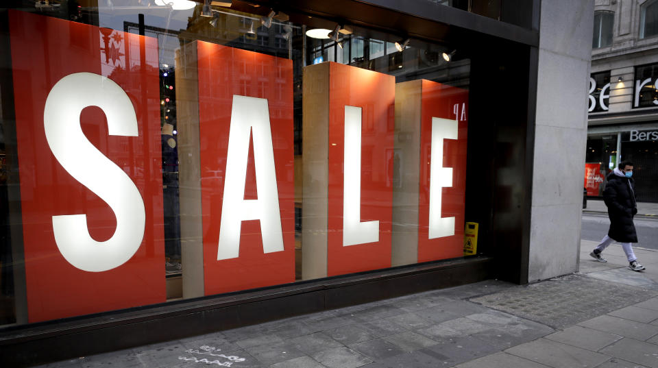 A sale sign in the window of a closed shop on Oxford Street in London, Saturday, Dec. 26, 2020. London is currently in Tier 4 with all non essential retail closed and people have been asked to stay at home, on what is usually one of the busiest retail days of the year with the traditional Boxing Day sales in shops. (AP Photo/Kirsty Wigglesworth)