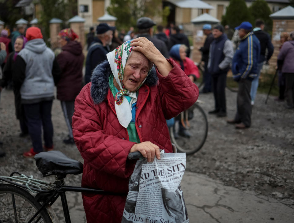 A local resident reacts as she waits for a car distributing humanitarian aid in an area recently liberated by Ukrainian Armed Forces, in the Kharkiv region