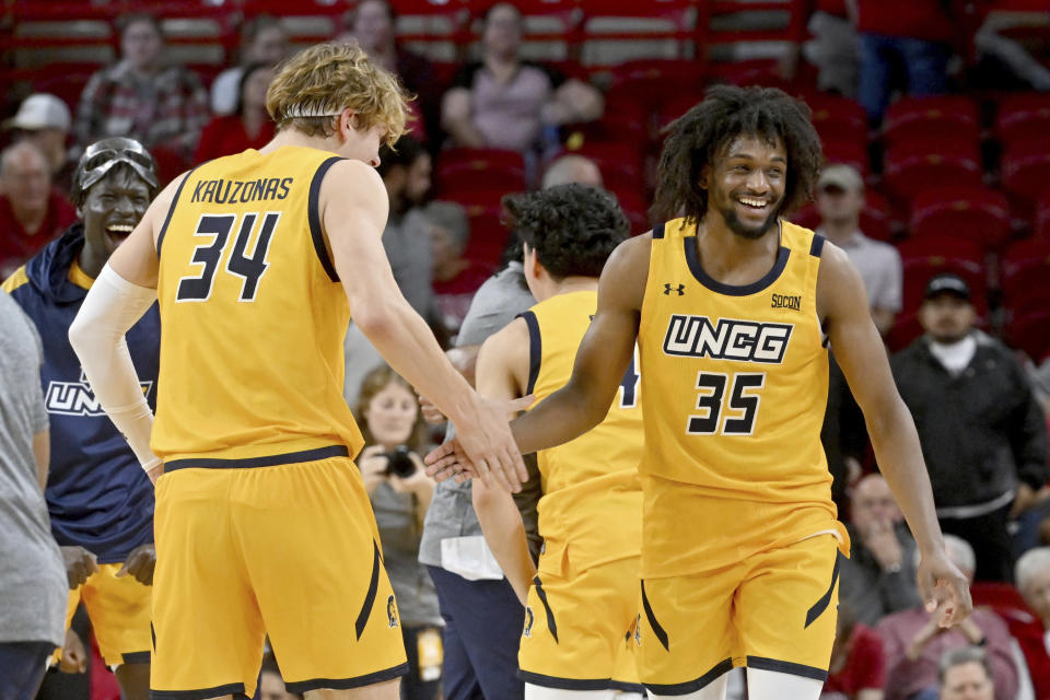 UNC Greensboro players Domas Kauzonas (34) and Akrum Ahemed (35) celebrate after defeating Arkansas 78-72 after an NCAA college basketball game Friday, Nov. 17, 2023, in Fayetteville, Ark. (AP Photo/Michael Woods)