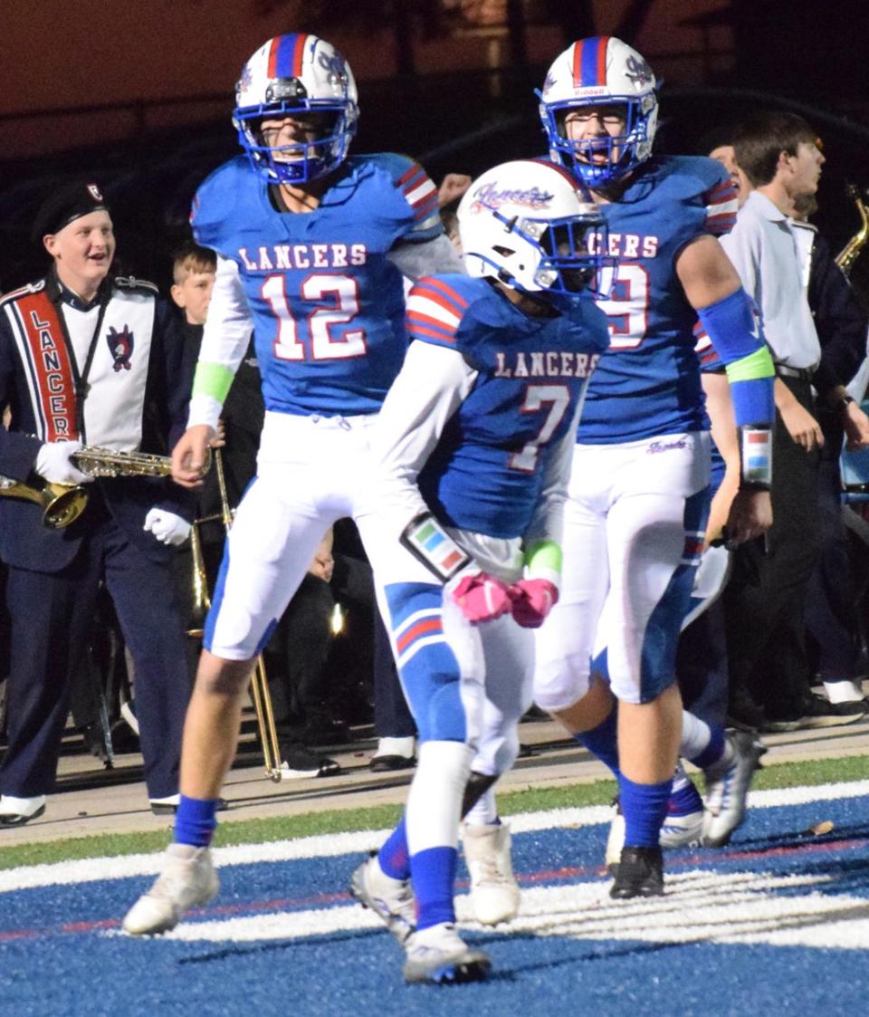 Lakewood junior Isaiah Mitchell (7), freshman Garrett Hardway (12) and senior Jacob Ellinger (59) celebrate Mitchell's touchdown after Hardway's blocked punt against Utica at Calhoun Memorial Field on Friday, Oct. 21, 2022. The host Lancers won 20-14 to earn their first victory of the season.