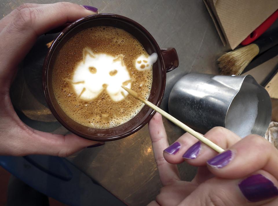 A worker makes the image of a cat on a "Cat'achino" at the cat cafe in New York April 23, 2014. The cat cafe is a pop-up promotional cafe that features cats and beverages in the Bowery section of Manhattan.