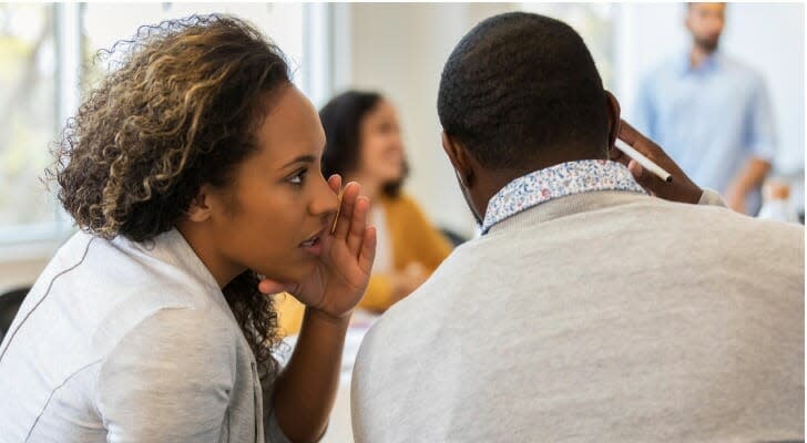 Businesswoman whispers to a colleague