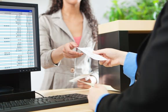 A teller handing a customer a check.