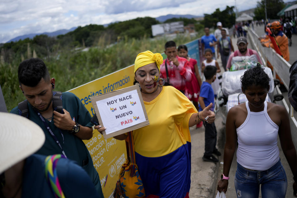 A supporters of Colombia's new President Gustavo Petro carrying a sign reading in Spanish "A new country is born today" crosses the border from Colombia to Venezuela in San Antonio, Venezuela, Sunday, Aug. 7, 2022. Colombia's incoming foreign minister and his Venezuelan counterpart announced in late July that the border, partially closed since 2015, will gradually reopen after the two nations restore diplomatic ties when Colombia's new president is sworn-in on Aug. 7. (AP Photo/Matias Delacroix)