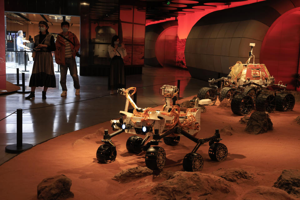 Visitantes pasan por un recinto el viernes 14 de mayo de 2021 en el que se exhiben sondas rodantes que simulan estar en Marte, en una exposición en Beijing. (AP Foto/Ng Han Guan)