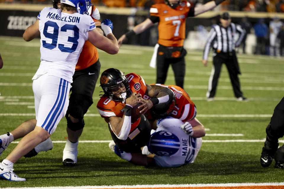 Oklahoma State running back Ollie Gordon II (0) dives over BYU defensive tackle Atunaisa Mahe (62) for a touchdown in the second half of an NCAA college football game Saturday, Nov. 25, 2023, in Stillwater, Okla. (AP Photo/Mitch Alcala)