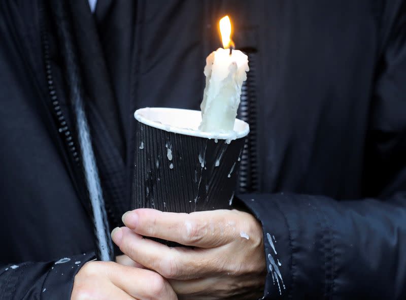 A mourner waiting for the funeral procession of John Hume holds a candle outside St Eugene's Cathedral in Londonderry