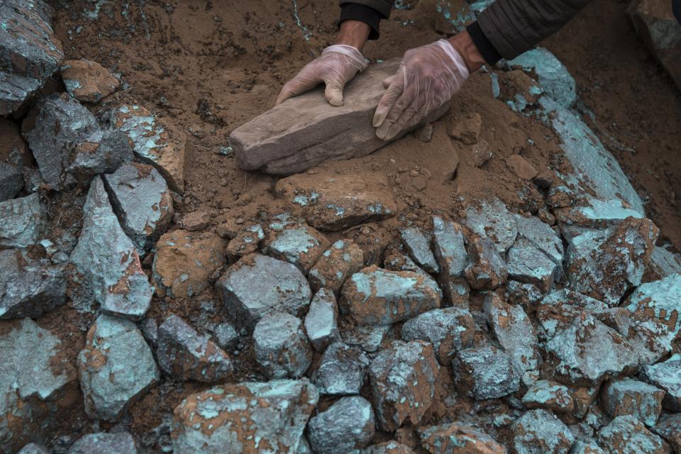 A relative uses rocks to decorate the tomb of Adrian Tarazona Manrique, 72, who died of COVID-19 complications, at the Nueva Esperanza cemetery on the outskirts of Lima, Peru, Thursday, May 28, 2020. (AP Photo/Rodrigo Abd)