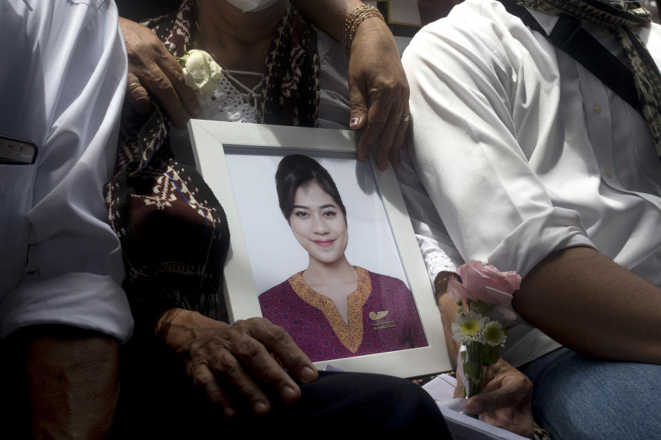 A relative holds a photo of Mia Tresetyani, a victim of the crash of Sriwijaya Air flight SJ-182 during her burial in Denpasar, Bali, Indonesia on Thursday, Jan. 21, 2021. The Indonesian leader on Wednesday reassured relatives of the passengers killed when the plane nosedived into the Java Sea that compensation is paid to family members struggled with grief. (AP Photo/Firdia Lisnawati)