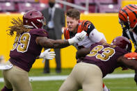 Cincinnati Bengals quarterback Joe Burrow (9) looses his helmet as he is tackled by Washington Football Team defensive tackle Jonathan Allen (93) and defensive end Chase Young (99), during the first half of an NFL football game, Sunday, Nov. 22, 2020, in Landover. (AP Photo/Susan Walsh)