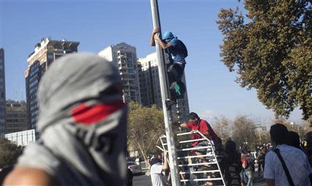 Masked demonstrators take part in the first rally against the government of Michelle Bachelet in Santiago, March 22, 2014. REUTERS/Pablo Sanhueza