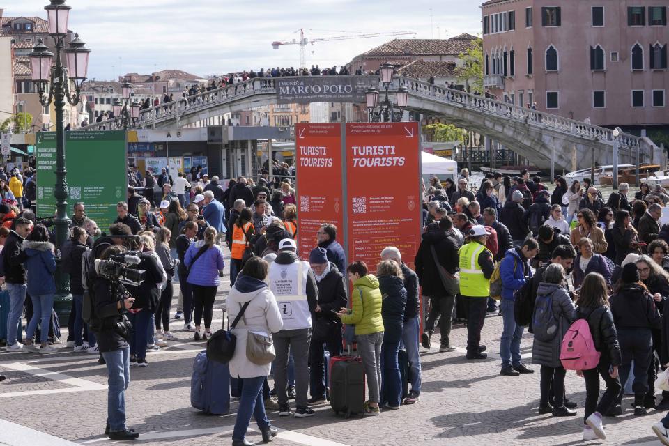 Asistentes comprueban códigos de acceso de los turistas ante la principal estación de tren de Venecia, el jueves 25 de abril de 2024. Ante la mirada de los medios del mundo, la frágil ciudad ribereña de Venecia inició un programa piloto el jueves para cobrar una cuota de entrada de unos 5 euros (unos 5,35 dólares) a los que visiten el lugar sólo por un día. (AP Foto/Luca Bruno)