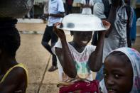 A girl poses with a metal bowl over her head on the sidelines of a protest against incumbent Malian President Ibrahim Boubacar Keita in Bamako