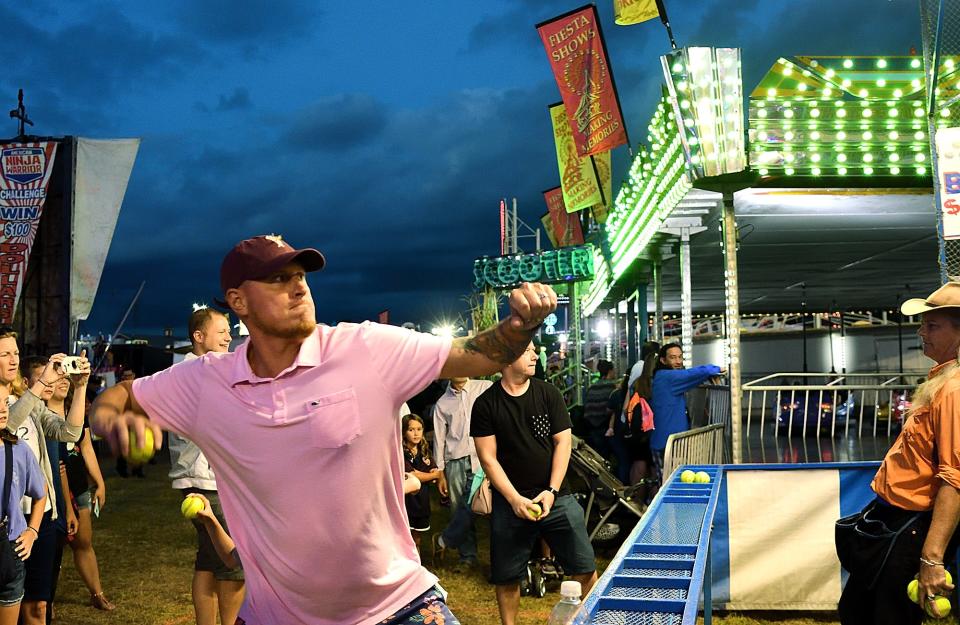 In a file photo, Jeffrey Taddeo of Newington hurls a baseball at a clown sitting in a dunk tank at the 2019 Woodstock Fair.