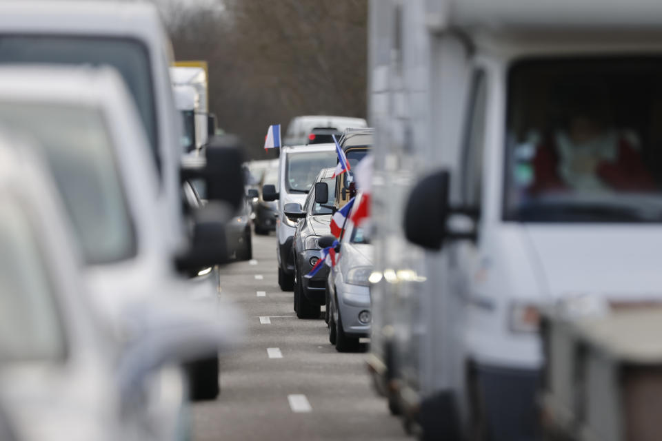 French flags ornate cars part of a convoy heading to Paris, Friday, Feb.11, 2022 in Strasbourg, eastern France. Authorities in France and Belgium have banned road blockades threatened by groups organizing online against COVID-19 restrictions. The events are in part inspired by protesters in Canada. Citing "risks of trouble to public order," the Paris police department banned protests aimed at "blocking the capital" from Friday through Monday. (AP Photo/Jean-Francois Badias)