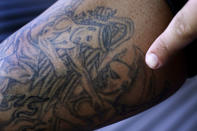 Mike Gilpatrick, who as a teenager was incarcerated at the Youth Development Center, points out one of his tattoos, of an angel battling a demon that was inked in prison, at his home, Wednesday, Sept. 8, 2021, in Nashua, N.H. Gilpatrick, 38, filed a lawsuit Monday Sept. 13, alleging he was physically and sexually abused at the former YDC in Manchester, which has been the target of a criminal investigation since 2019 and is slated to close in 2023. (AP Photo/Charles Krupa)