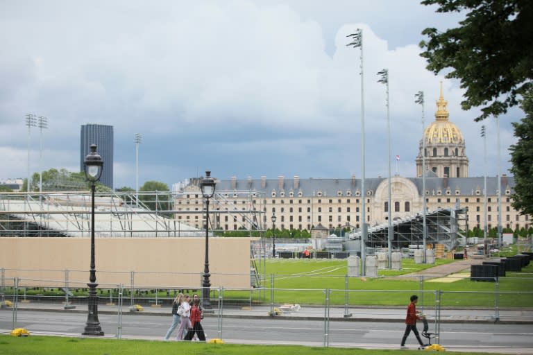 Unos transeúntes pasan junto a una instalación temporal en construcción para los Juegos Olímpicos de París 2024, el 31 de mayo de 2024 en la explanada de los Inválidos, en el centro de la capital francesa (Sami Karaali)