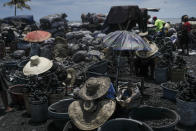 Vendors wear hats for shade as they sell cooking coal at a market in Cap-Haitien, Haiti, Thursday, July 22, 2021. The city of Cap-Haitien will hold events to honor slain President Jovenel Moïse on Thursday ahead of Friday’s funeral. (AP Photo/Matias Delacroix)