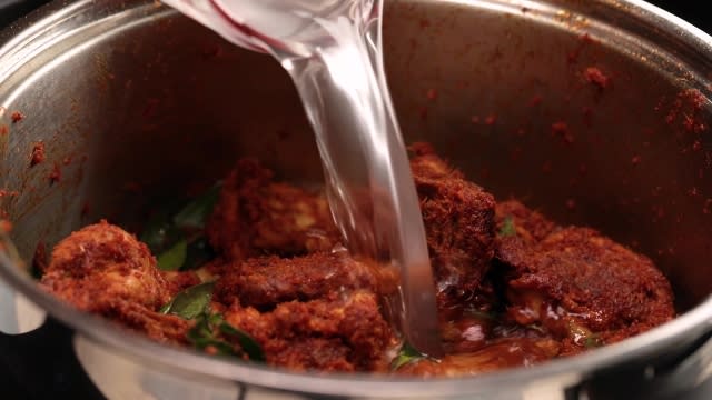 Pouring coconut water to rendang paste