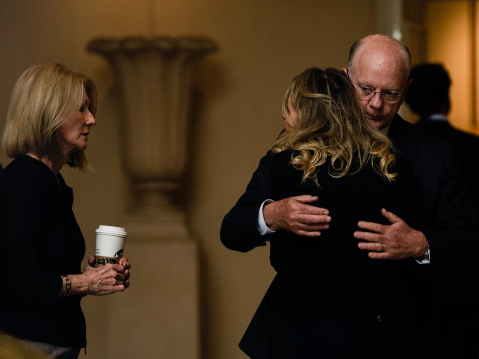 Elizabeth Holmes hugging her father, Christian Holmes IV as her mother, Noel Holmes, looks on.