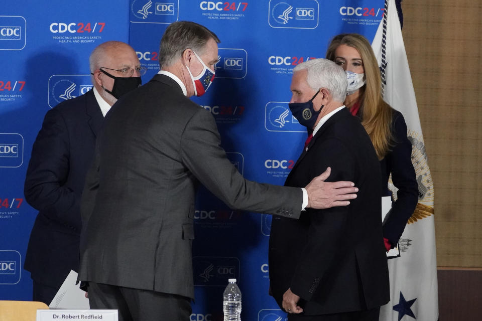 Vice President Mike Pence, right, speaks with Sen. David Perdue, R-Ga., and Sen. Kelly Loeffler, R-Ga, as Centers for Disease Control and Prevention director Dr. Robert Redfield looks on after a meeting on COVID-19 at the CDC Friday, Dec. 4, 2020, in Atlanta. (AP Photo/John Bazemore)