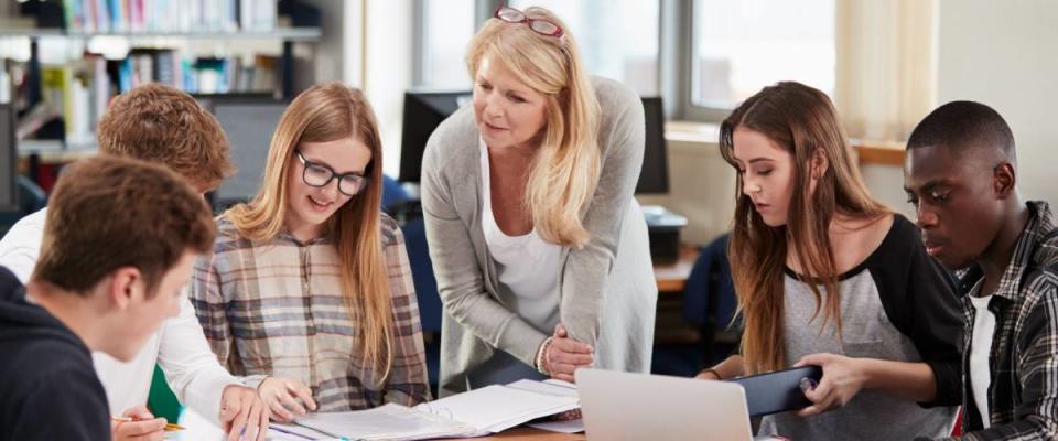 Female Teacher Working With College Students In Library