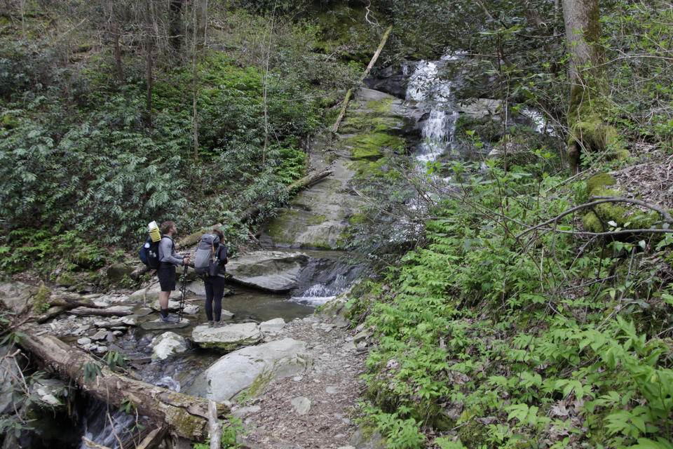 In this March 30, 2020, photo, Alexandra Eagle, right, and Jonathan Hall stand in front of a waterfall on the Appalachian Trail in Cosby, Tenn. The couple planned the to hike from Georgia to Maryland until coronavirus concerns forced them off the trail. (AP Photo/Sarah Blake Morgan)